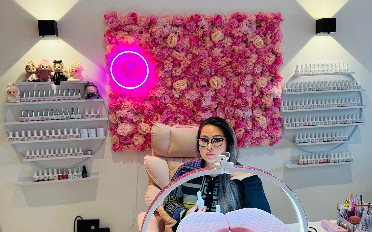 Kim aan haar werktafel voor de bloemenwand met de roze neon