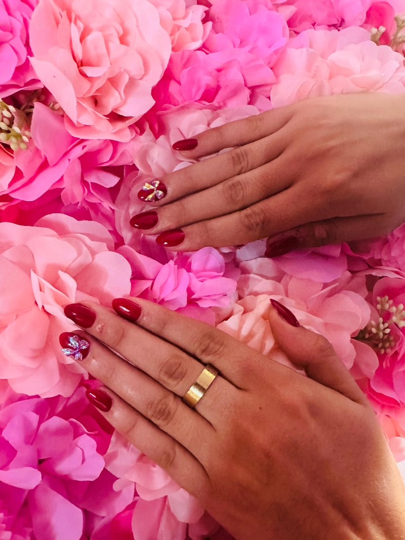 Rode nagels met zilveren nail art voor de roze bloemenwand