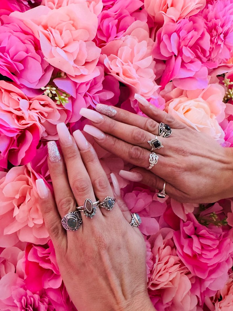 Lange lichtroze nagels met ringen voor de bloemenwand