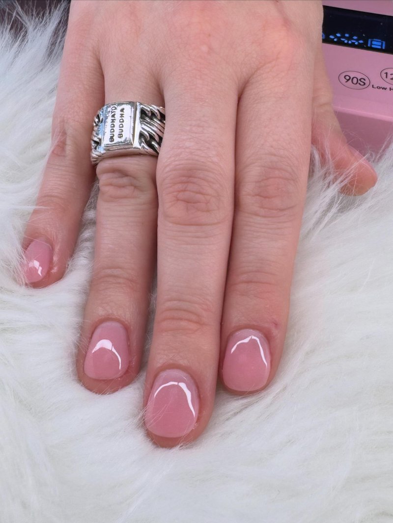 Glanzende roze nagels met een zilveren ring